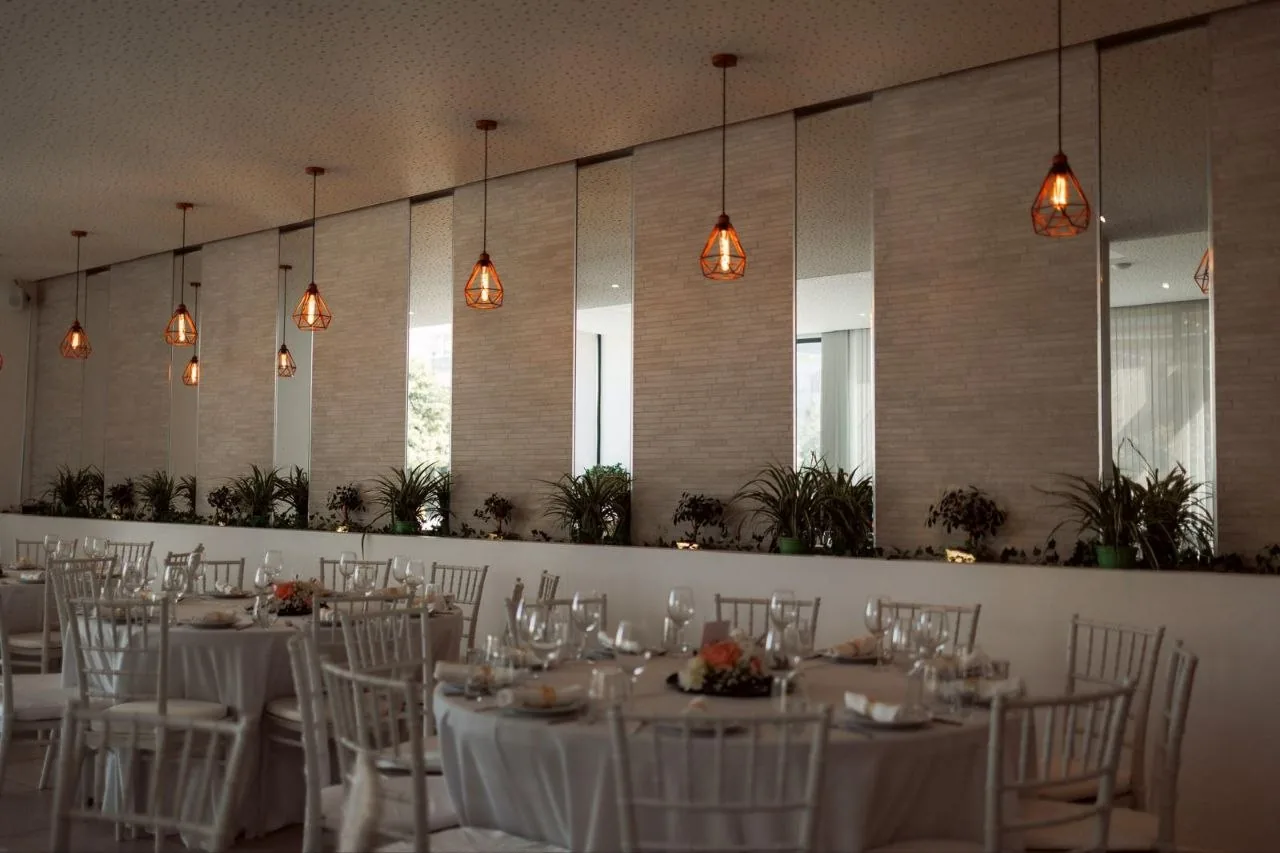 Sala de banquetes com mesas longas e luzes suspensas