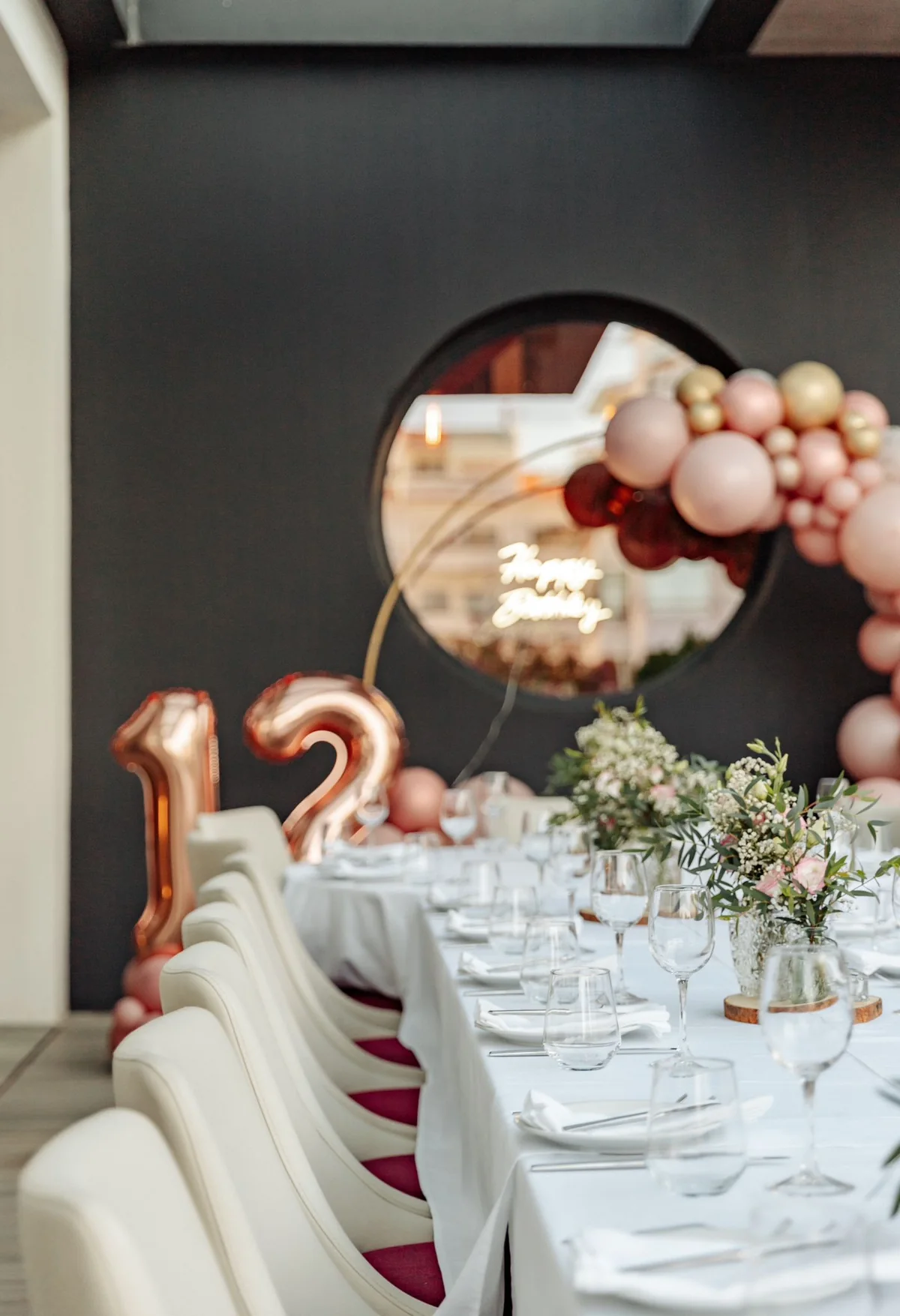 Mesa longa posta para uma festa privada, com balões e arranjos florais