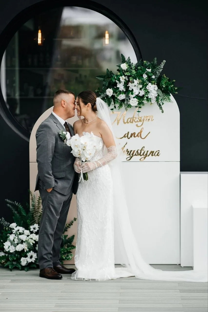 Casal junto à decoração floral com os seus nomes
