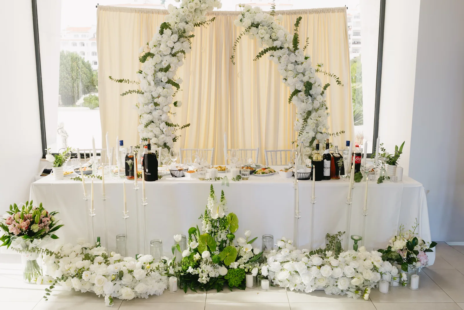 Mesa dos noivos com cortinado e decoração floral