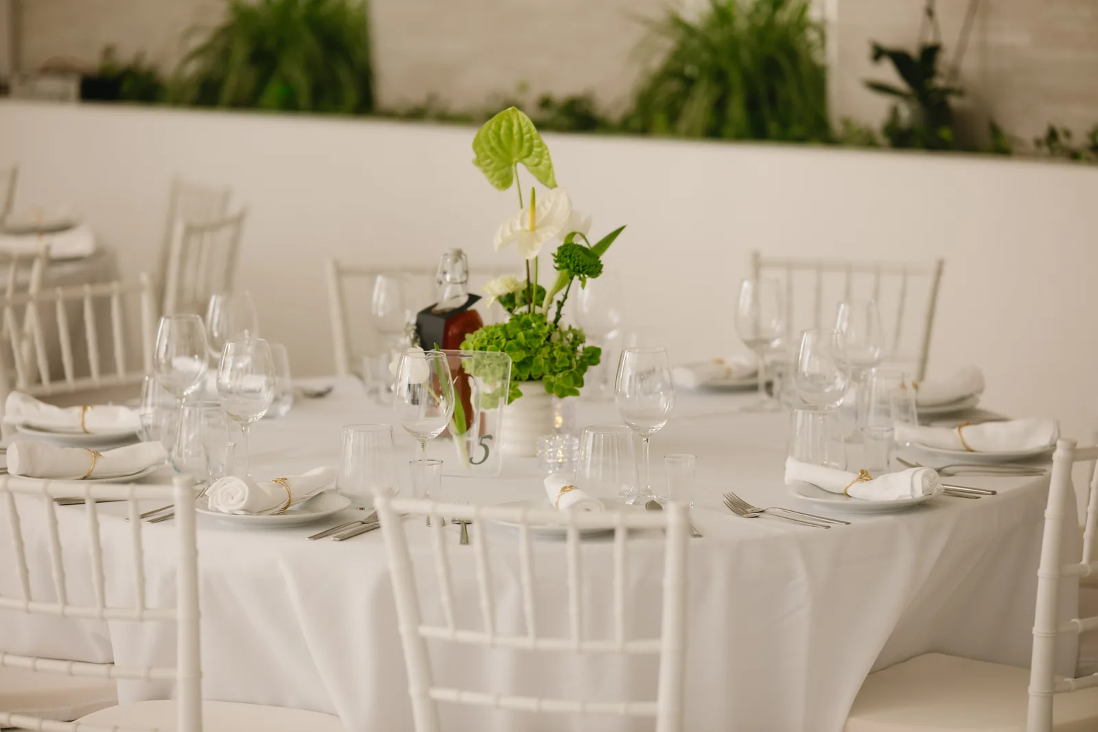 Mesa redonda posta com arranjo floral e cadeiras chiavari
